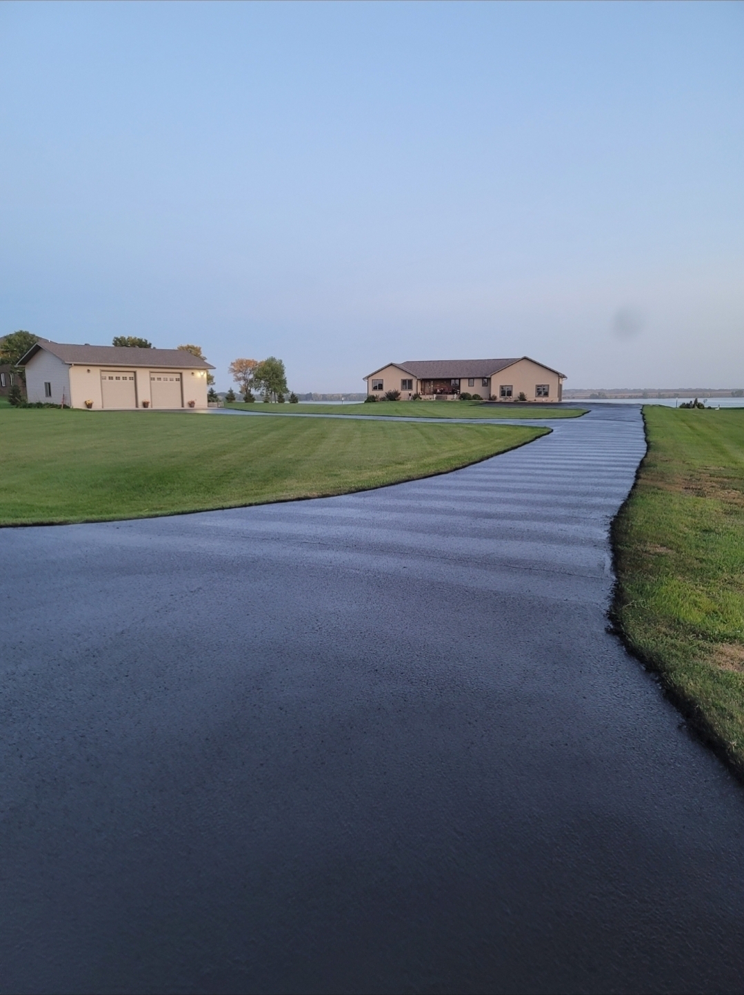 Worker applying sealcoat to a driveway